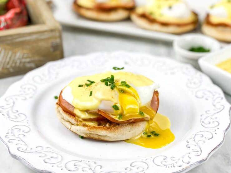 This Eggs Benedict recipe features buttery English muffins, back bacon, & poached eggs, all smothered in an easy blender hollandaise sauce.
