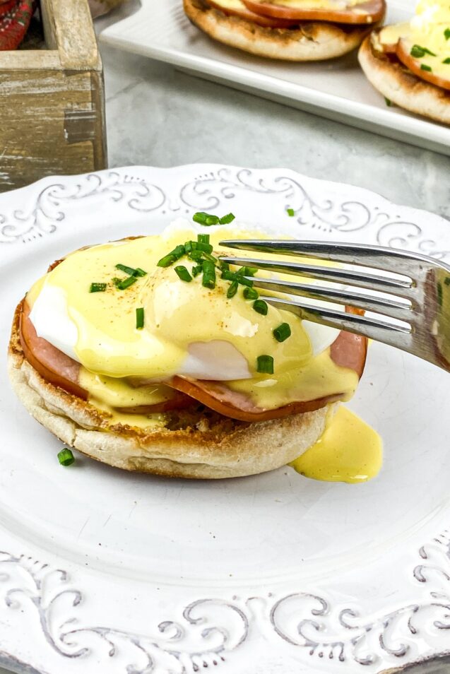 This Eggs Benedict recipe features buttery English muffins, back bacon, & poached eggs, all smothered in an easy blender hollandaise sauce.