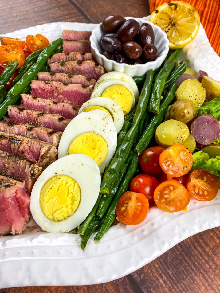 Niçoise Salad is a French composed salad, made of tomatoes, hard-boiled eggs, Niçoise olives and tuna. This version features seared Ahi Tuna.