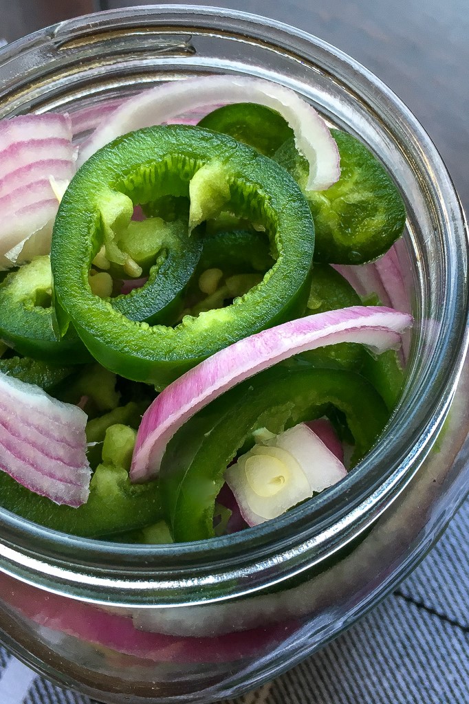Sliced Jalapenos and red onions in a mason jar.