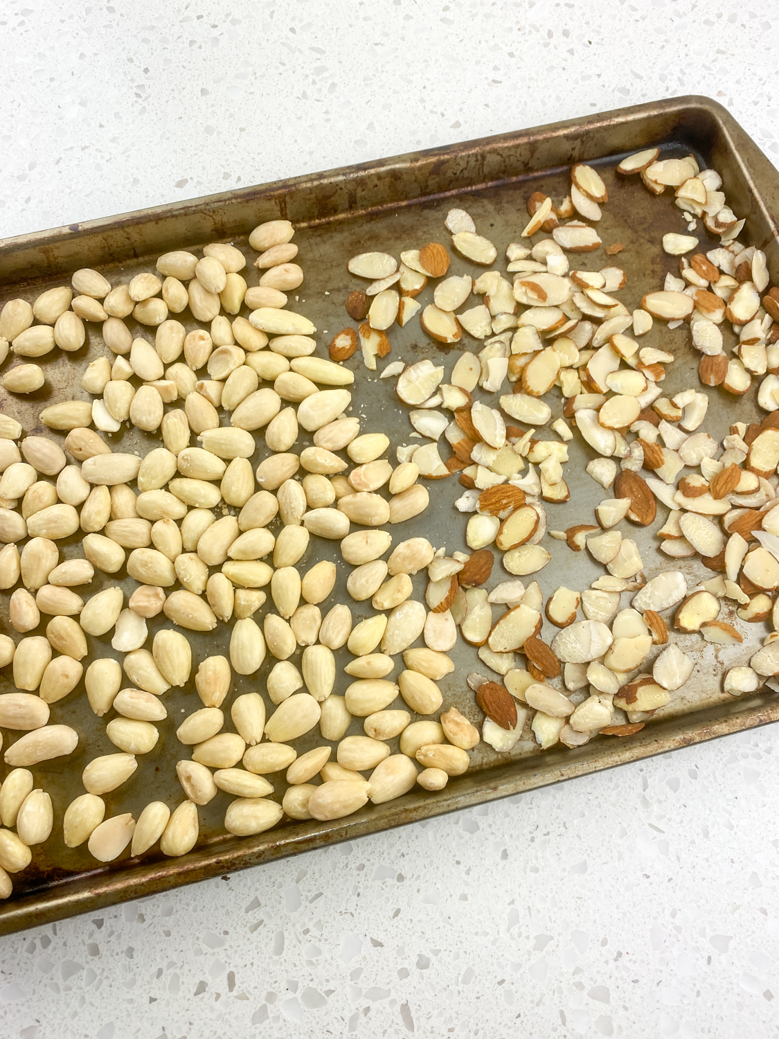 Whole and sliced almonds laid out on a baking sheet.