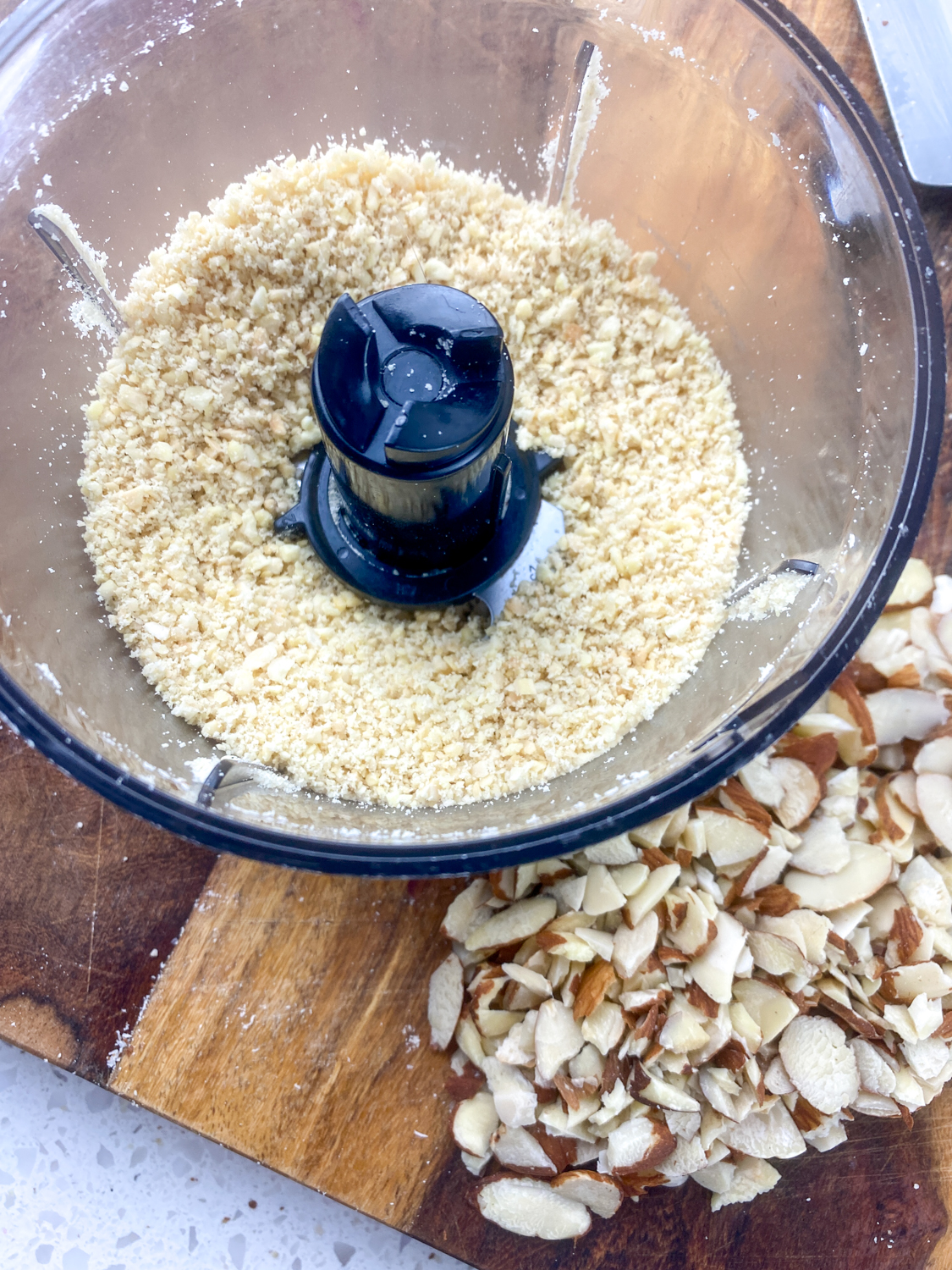 Whole roasted almonds being ground up in a food processor.