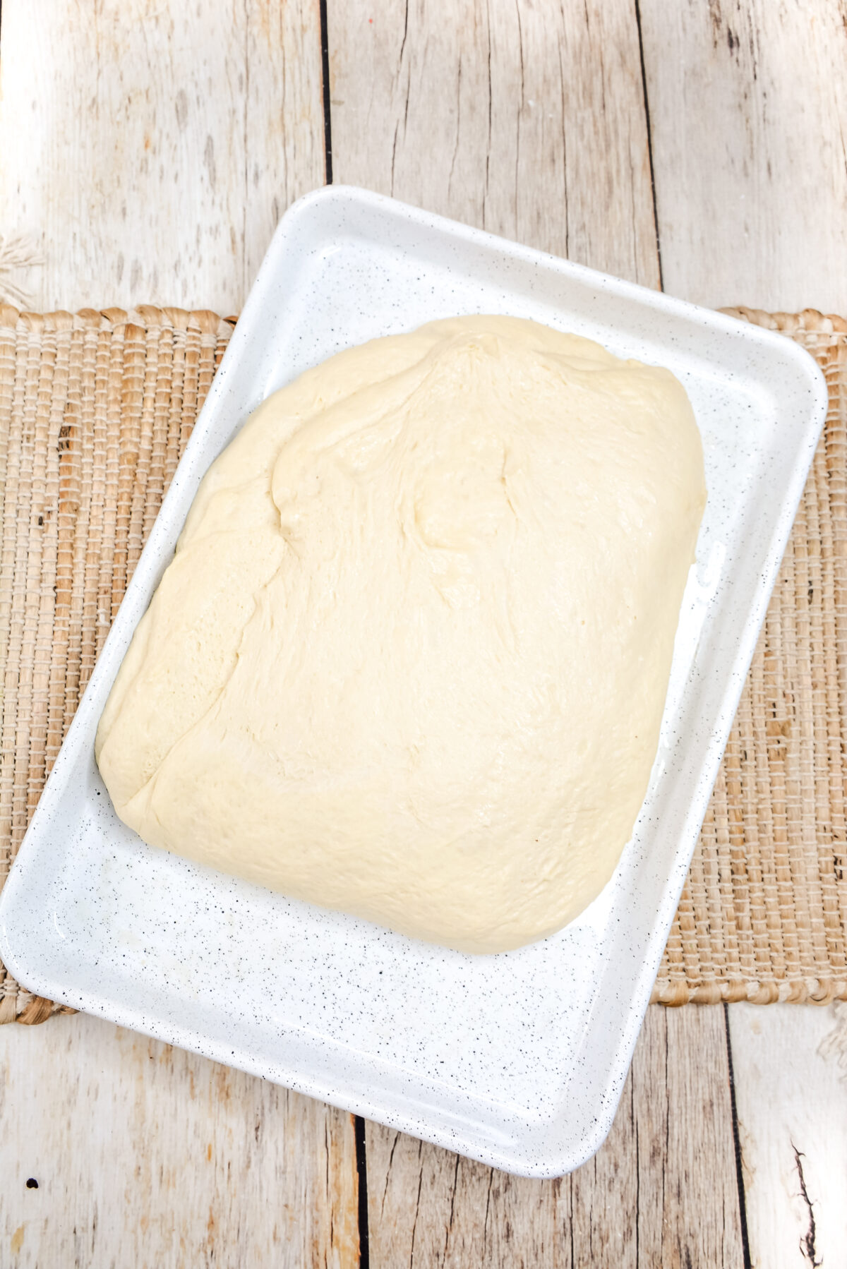 Dough in a sheet pan formed into a rough rectangle.