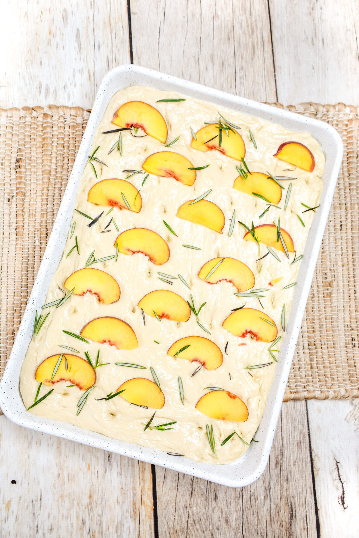 Peach slices and thyme arranged over the quarter sheet pan