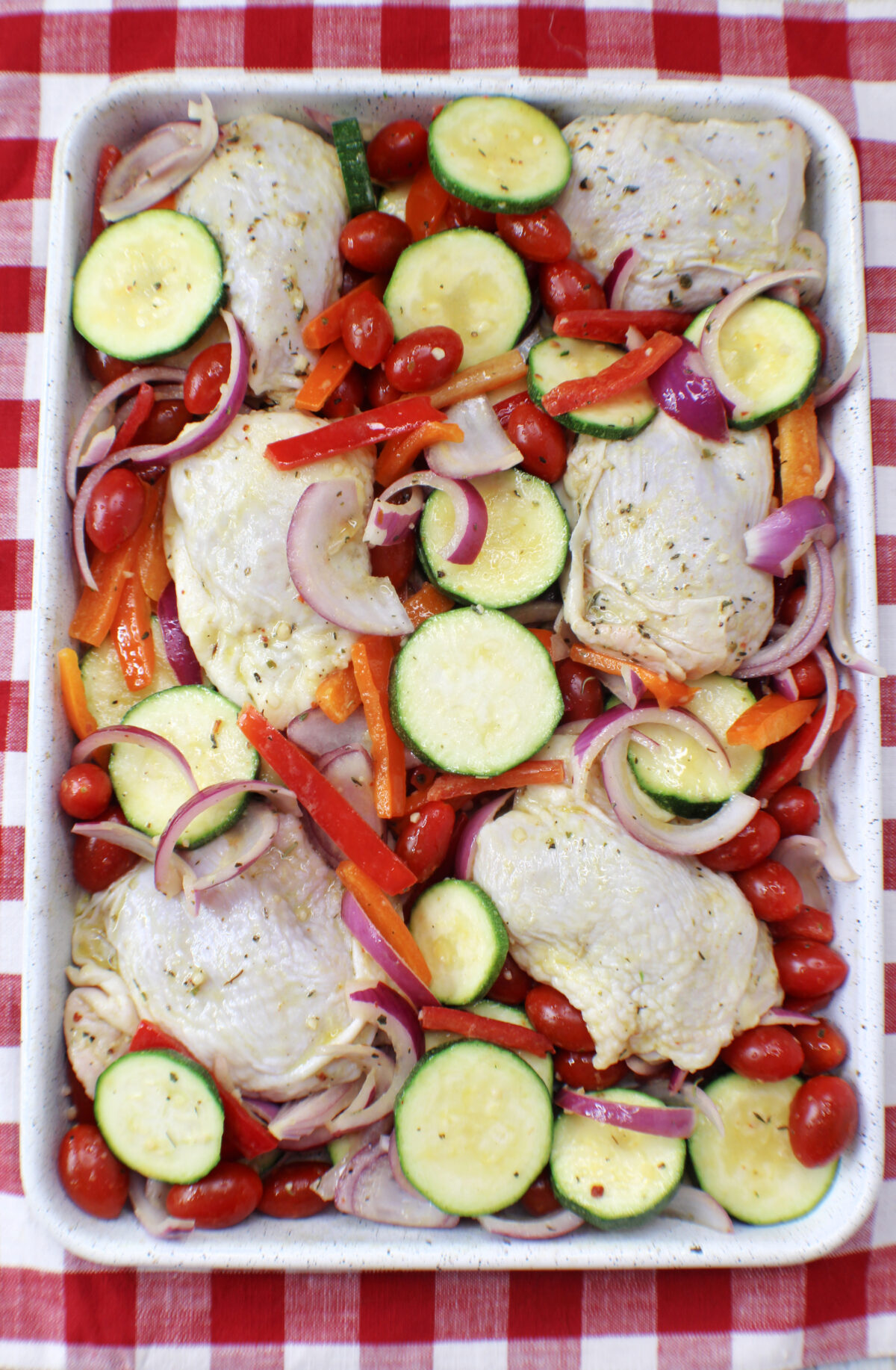 Chicken added to the vegetables on the sheet pan.